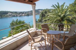 balcón con sillas, mesas y vistas al agua en Apartman Klara en Lumbarda