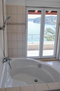 a white bath tub in a bathroom with a window at Apartman Klara in Lumbarda