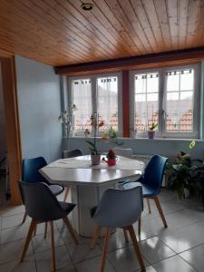 einen Tisch und Stühle in einem Zimmer mit Fenstern in der Unterkunft Gîte Le Jardin de Hermolsheim. Alsace très spacieux in Mutzig