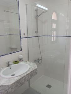 ein weißes Bad mit einem Waschbecken und einer Dusche in der Unterkunft Casa Ozzy in Costa Calma