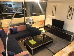 sala de estar con sofá y TV en Apartamento Parque Arauco Kennedy, en Santiago