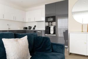 ein Wohnzimmer mit einem blauen Sofa und einer Küche in der Unterkunft Lovely En-suite Flat with Balcony and Parking. in London