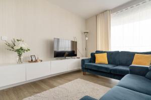 ein Wohnzimmer mit einem blauen Sofa und einem TV in der Unterkunft Lovely En-suite Flat with Balcony and Parking. in London