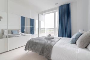 ein weißes Schlafzimmer mit einem großen Bett und einem großen Fenster in der Unterkunft Lovely En-suite Flat with Balcony and Parking. in London