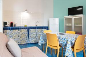 Elimi Favignana Apartments - Residence in città في فافينانا: مطبخ مع طاولة وكراسي صفراء وثلاجة