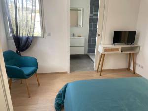een kamer met een bed, een stoel en een televisie bij Villa Pieds dans l’eau in Carry-le-Rouet