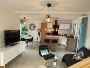 een woonkamer en een keuken met een bank en een televisie bij Villa Pieds dans l’eau in Carry-le-Rouet