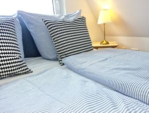 a bed with blue and white striped sheets and a lamp at Paulchens Kajüte in Glücksburg
