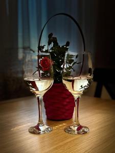 twee glazen wijn zittend op een tafel met een vaas bij Apartament Brzeźno Plaża in Gdańsk