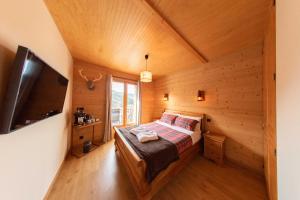 um quarto num chalé de madeira com uma cama e uma televisão em La Masia Del Taulat Chambres d´Hôtes em Llo