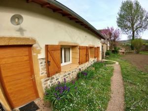 a house with wooden doors and flowers in the yard at EVASION NATURE ET CONVIVIALITÉ in Sourcieux-les-Mines