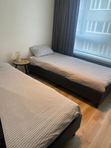 twee eenpersoonsbedden in een kamer met een raam bij Portofino - luxe appartement met lateraal zeezicht in Oostende