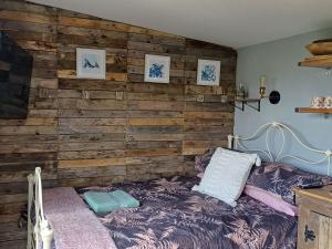 a bedroom with a wooden accent wall with a bed at Rhubarb Hut, set in the beautiful Cornish Countryside in Helston