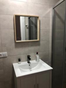 een badkamer met een witte wastafel en een spiegel bij APARTAMENTOS MESTRE in Ayamonte