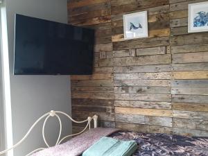 a bedroom with a wooden wall with a flat screen tv at Rhubarb Hut, set in the beautiful Cornish Countryside in Helston