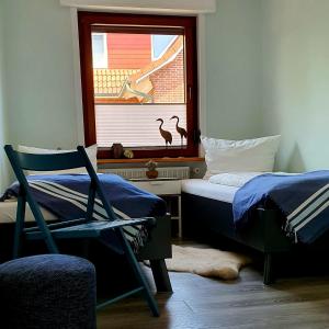 Un dormitorio con una cama y una silla y una ventana. en Ferienhaus Siebrands, en Greetsiel