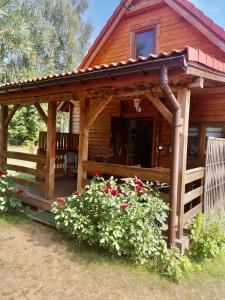 uma cabana com um alpendre e flores à sua frente em Domek z bala Mazury em Orzyny