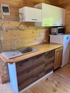 a kitchen with wooden cabinets and a sink and a refrigerator at Domek z bala Mazury in Orzyny