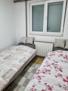 um quarto com 2 camas e 2 janelas em Apartman- Sarajevo em Sarajevo