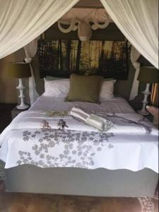 a bed with a white comforter with dolls on it at Canyon guest villa in Hoedspruit