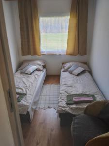 two beds in a small room with a window at Na Piaskach Domek nad rzeką Agroturystyka in Narol