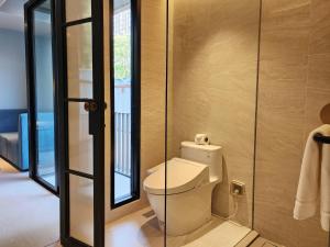 a bathroom with a toilet and a glass door at The SACHA Apart-Hotel Thonglor in Bangkok