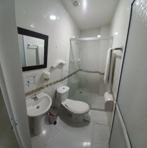 een witte badkamer met een toilet en een wastafel bij HOTEL SAN ADOLFO in Apartadó