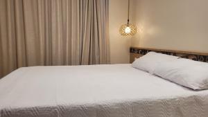 a bedroom with a bed with white sheets and a lamp at Villa Andorinha -Apto01 in Mucugê