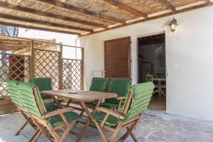 a wooden table and green chairs on a patio at MAREMMA TOSCANA [PISCINA & IDROMASSAGGIO] in Grosseto