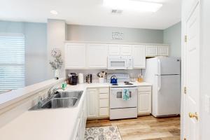 a white kitchen with a sink and a refrigerator at Sweet Retreat in Sunset Beach
