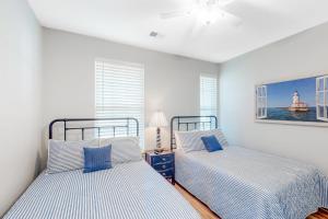 two beds in a room with two windows at Sweet Retreat in Sunset Beach