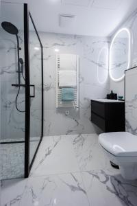 a white bathroom with a shower and a toilet at Villa Bauhaus Wellness Apartman Fsz. 3 in Siófok