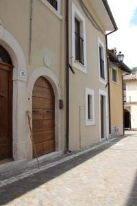 - un bâtiment avec une porte en bois dans une rue dans l'établissement La Rosa dei Pastori, à San Demetrio neʼ Vestini