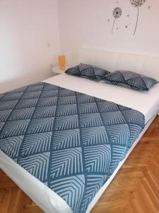 a bed with a blue and white comforter and two pillows at Apartment The View Costabella no.2 in Rijeka