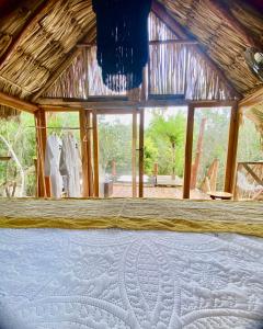 a bed in a room with a thatch roof at Nuscaa Boutique Tree House & Spa in Puerto Morelos