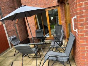 un grupo de sillas y una sombrilla en un patio en Entire -4 Bedrooms Detached House with Driveway en Nottingham