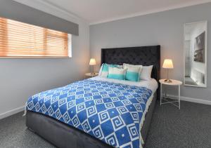 a bedroom with a blue and white bed and a window at 20 Cae Du in Abersoch
