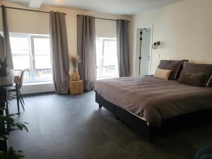 1 dormitorio con cama, mesa y ventanas en Loogiez, en Tongeren