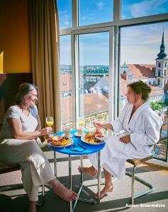 twee vrouwen aan tafel met eten en wijn bij Hotel Avion - National Cultural Monument - ICONIC HOUSES ORG in Brno