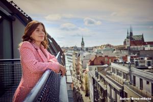 een vrouw op een balkon met uitzicht over een stad bij Hotel Avion - National Cultural Monument - ICONIC HOUSES ORG in Brno