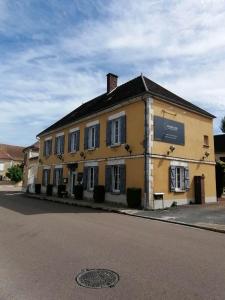 a large yellow building on the side of a street at LOGIS Hôtel & Restaurant Le Soleil D'or in Montigny-la-Resle