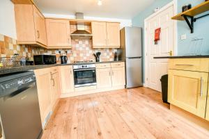 a kitchen with wooden floors and stainless steel appliances at Beech Court House By Horizon Stays in Widdrington