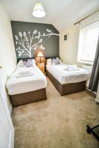 1 Schlafzimmer mit 2 Betten und einer Wand mit einem Baumbild in der Unterkunft Beech Court House By Horizon Stays in Widdrington