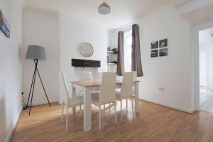 a dining room with a table and white chairs at A Perfect 3BD Home away from Home Canton Cardiff in Cardiff