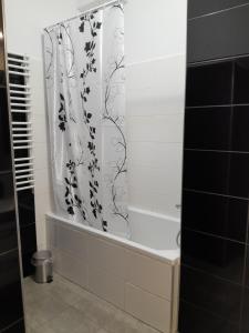 a bathroom with a shower curtain and a tub at Apartament Królewiecka 54b/26 in Mrągowo