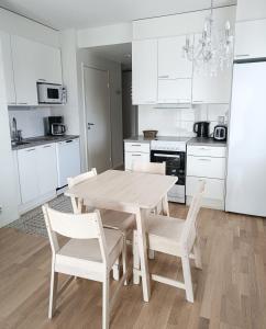 biała kuchnia z drewnianym stołem i krzesłami w obiekcie North Path Apartments w mieście Rovaniemi