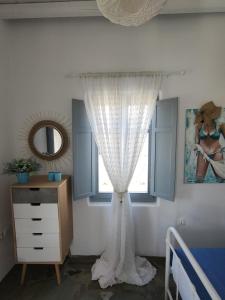 a bedroom with a window with a curtain and a dresser at Scarpathia House in Katapola