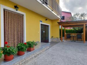 ein gelbes Haus mit drei Topfpflanzen auf einer Terrasse in der Unterkunft Soba Gracijela in Motovun