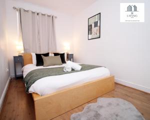 1 dormitorio con 1 cama grande con marco de madera en Spacious 3 Bedroom Duplex Apartment On Cardiff Bay - Free Parking & WIFI By EKLIVING LUXE Short Lets & Serviced Accommodation, en Cardiff