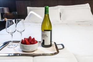 un tavolo con una bottiglia di vino e una ciotola di fragole di Hotel Mosaico & Residence a Ravenna